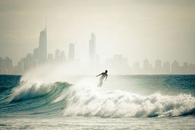 Man surfing in sea against city