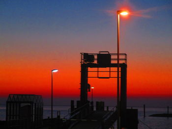 Silhouette tower by sea against sky during sunset