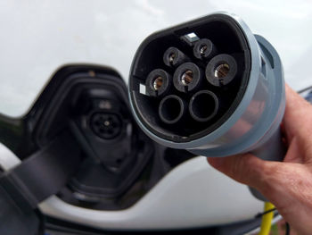 Close-up of hand holding electrical equipment by car