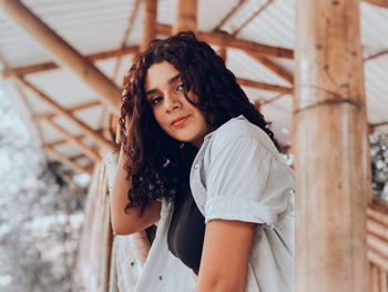 Portrait of beautiful young woman standing on railing