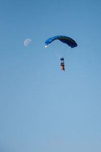 Low angle view of person paragliding against clear blue sky