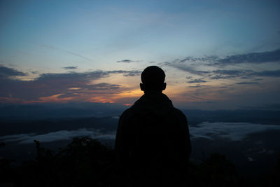 Rear view of silhouette man standing against sky during sunset