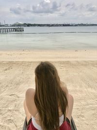 Rear view of woman sitting at beach