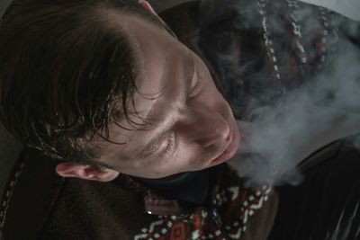 Close-up of man emitting smoke