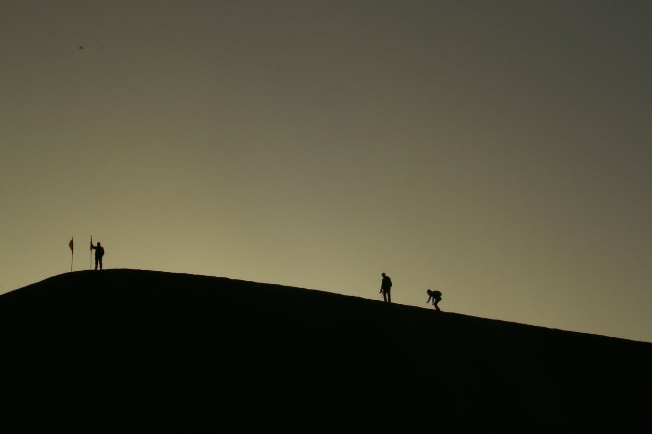 silhouette, copy space, men, clear sky, low angle view, sunset, lifestyles, leisure activity, outline, unrecognizable person, dusk, standing, sky, full length, nature, tranquility, tranquil scene