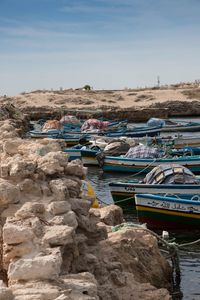 Boats moored on sea shore against sky