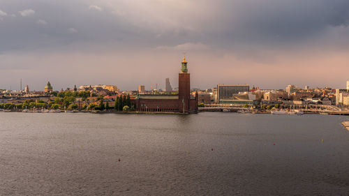 Stockholm buildings at waterfront against cloudy sky