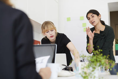 Mid adult businesswoman talking with female colleague in office