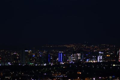 Illuminated cityscape against sky at night