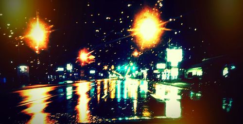 Illuminated cars on wet street at night