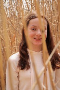 Portrait of smiling young woman standing against plants