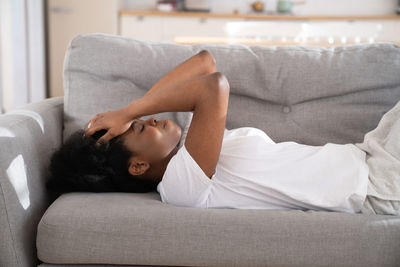 Midsection of woman resting on sofa at home