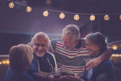 Happy senior couples toasting wine at night