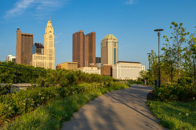 Road amidst trees and buildings against sky