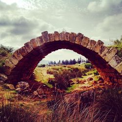 Arch bridge against cloudy sky