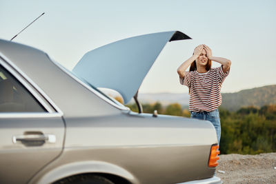 Rear view of woman with umbrella on car