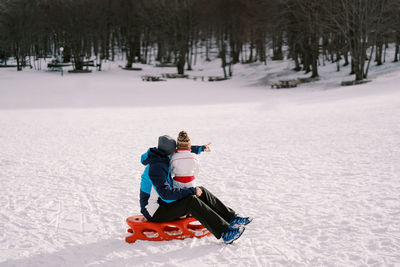 Rear view of woman skiing on snow covered field