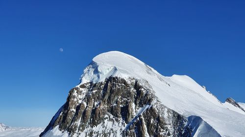 Scenic view of snowcapped mountains against clear blue sky