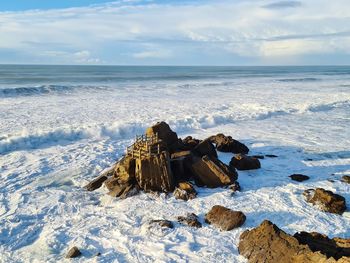 Scenic view of rocks on beach against sky