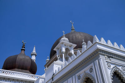 Low angle view of mosque against clear blue sky