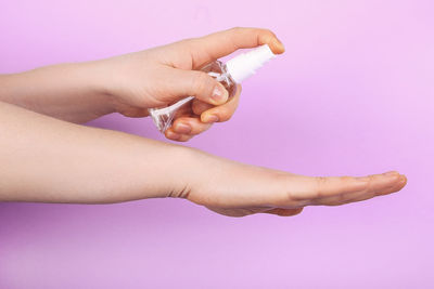 Close-up of woman hand against pink background