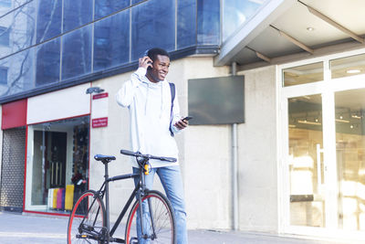 Man with bicycle standing against building