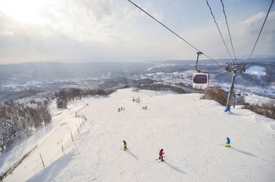 High angle view of people skiing on snowcapped mountain against sky