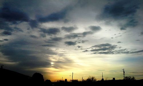 Low angle view of silhouette trees against cloudy sky
