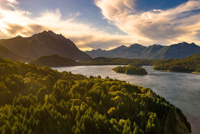 Scenic view of lake by mountains against sky during sunset