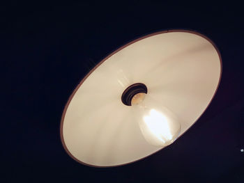 Low angle view of illuminated light bulb against sky at night