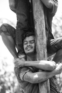 Close-up of man embracing pole while playing panjat pinang