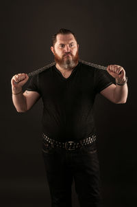 Portrait of man standing against black background