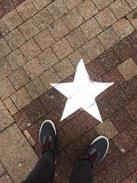 Low section of man standing by star shape on footpath