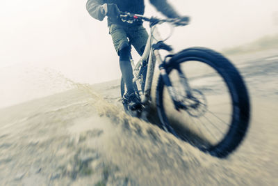 Low section of man riding bicycle on road