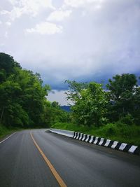 Empty road by trees against sky