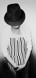 Midsection of woman wearing hat standing against white background