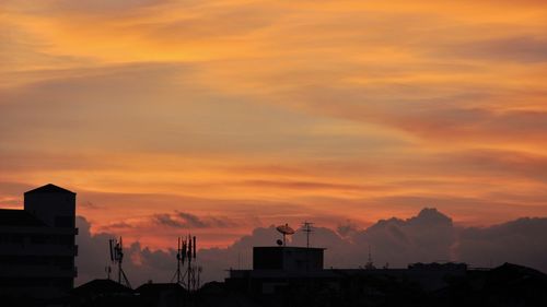 Silhouette houses against sky during sunset