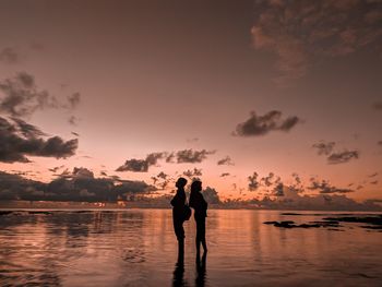 Silhouette people standing at beach against sky during sunset