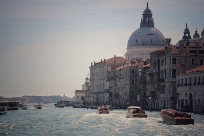 Buildings by river against sky