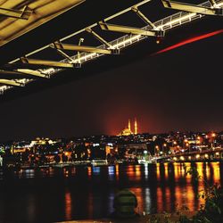 Illuminated city by river at night