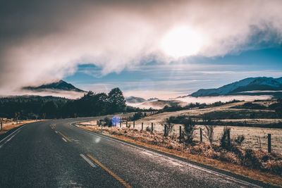 Road leading towards mountains against sky