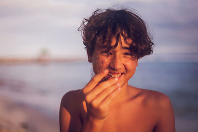 Portrait of shirtless boy at beach against sky