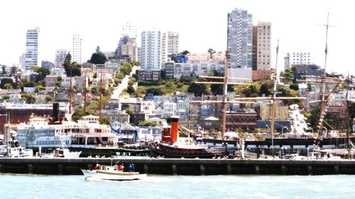 Boats moored at harbor in city