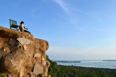 People on rock by sea against sky