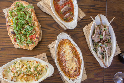 An assortment of italian dishes are spread out on a wooden table