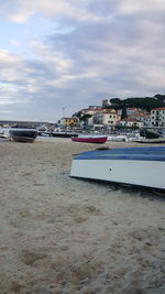 Boats in harbor against cloudy sky