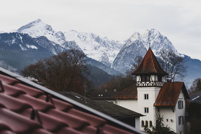 Houses by snowcapped mountains against sky