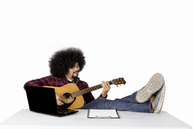 Man playing guitar against white background
