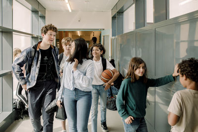 Male and female students talking in school corridor during break