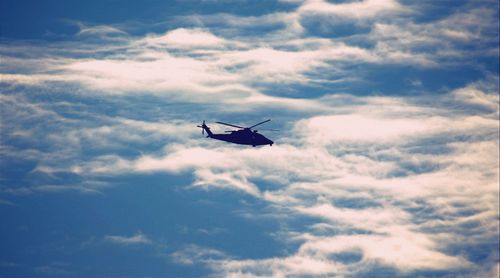 Side view of silhouette helicopter against clouds